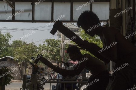 workers pound sheets of Gold leaf at a Gold pounder Factory the City of Mandalay in Myanmar in Southeastasia.