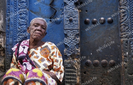 Eine Frau aus Zanzibar in traditionelle Kleidung im Portrait inmitten der Altstadt Stone Town der Hauptstadt Zanzibar Town auf der Insel Zanzibar welche zu Tansania gehoert.         