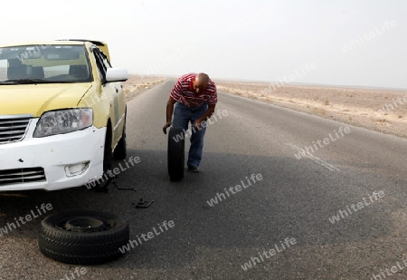 A flat tire on a Taxi on the Desertroad 65 near the Towns Safi and Aqaba in Jordan in the middle east.