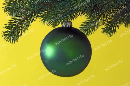 Dekorative Weihnachtskugel an einem Tannenzweig auf gelbem Hintergrund