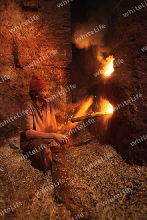 A men heat up Water for a Hammam or Arab Bath in the old City in the historical Town of Fes in Morocco in north Africa.