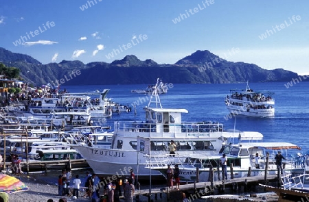 People at the coast of Lake Atitlan mit the Volcanos of Toliman and San Pedro in the back at the Town of Panajachel in Guatemala in central America.   