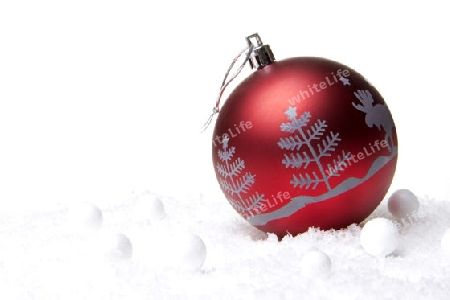 rote Christbaumkugel mit Tannenbaum auf Schnee