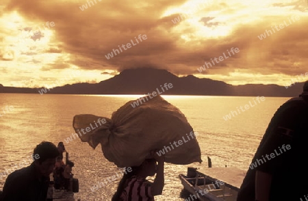 People at the coast of Lake Atitlan mit the Volcanos of Toliman and San Pedro in the back at the Town of Panajachel in Guatemala in central America.   