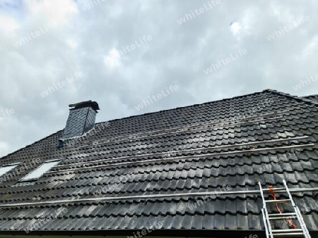 View at the roof tiles and a ladder of a residential house during roof repair