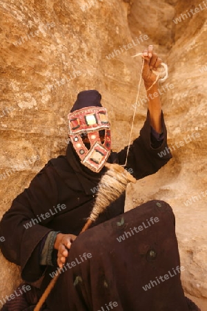 a Beduin women at work to spinning woll in the Temple city of Petra in Jordan in the middle east.