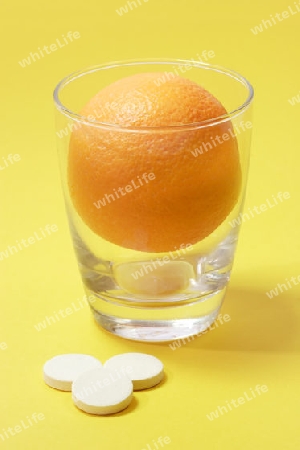 Orange mit einem Glas und Brausetabletten auf hellem Hintergrund