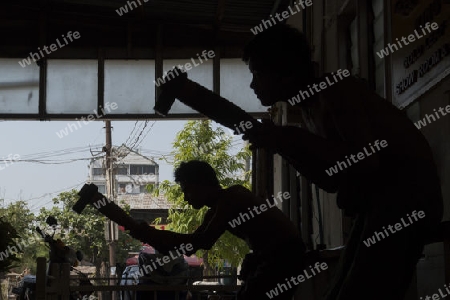 workers pound sheets of Gold leaf at a Gold pounder Factory the City of Mandalay in Myanmar in Southeastasia.