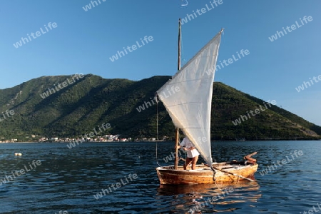 Ein Segelboot vor dem Dorf Persat in der inneren Bucht von Kotor in Montenegro im Balkan am Mittelmeer in Europa.