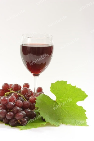 Rotwein mit roten Trauben auf hellem Hintergrund