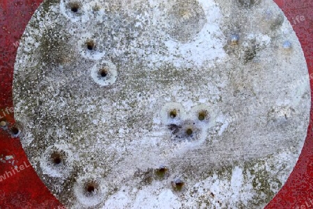 Detailed close up of bullet holes from gun shots in a german traffic sign