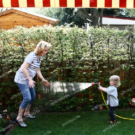 Kind spritzt Frau mit Wasser nass2