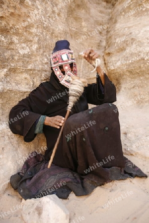 a Beduin women at work to spinning woll in the Temple city of Petra in Jordan in the middle east.