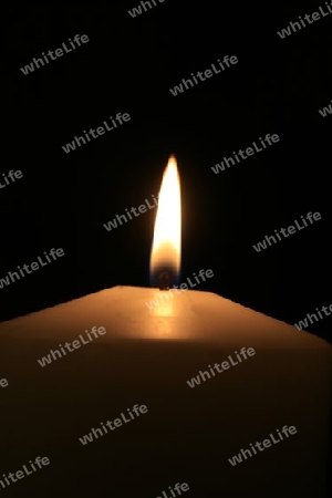 eine weisse brennende Kerze mit schwarzem Hintergrund