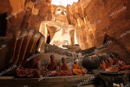 Moenche bestaunen die Buddha Figur  im Wat Si Chum Tempel in der Tempelanlage von Alt-Sukhothai in der Provinz Sukhothai im Norden von Thailand in Suedostasien.