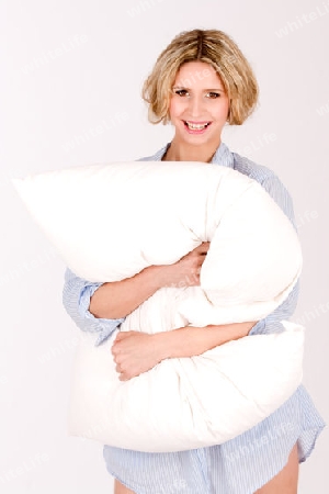 blonde Haaren stehend mit Kissen Kissen. Sie traegt ein Nachthemd und laechelt / blonde hair, standing with pillow cushions. She is wearing a nightgown and smiles