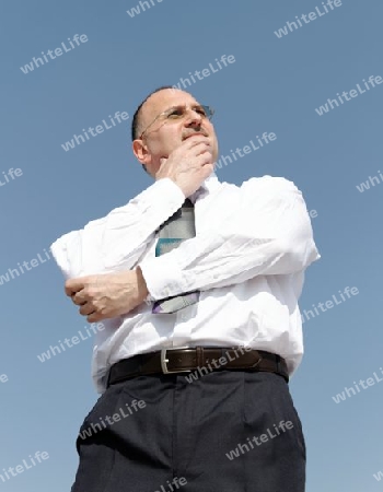 thoughtful businessman outdoors with blue background