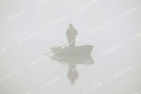 Angler mit Boot im Nebel