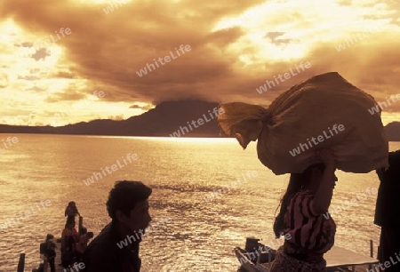 People at the coast of Lake Atitlan mit the Volcanos of Toliman and San Pedro in the back at the Town of Panajachel in Guatemala in central America.   