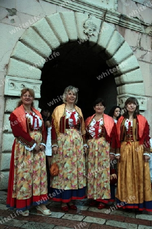 Trachtenfrauen vor dem Tor der Altstadt von Kotor  in der inneren Bucht von Kotor in Montenegro im Balkan am Mittelmeer in Europa.