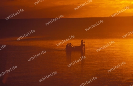 Ein Fischerboot in der Abendstimmung beim Horel Coco de Mer auf der Insel Praslin auf den Seychellen Inseln mit dem Meer des Indische Ozean.  