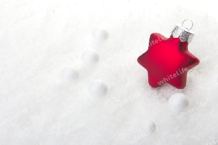 rote Christbaumkugel als Weihnachtsstern auf Schnee 