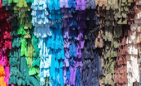 Detailed close up view on samples of zippers in different colors found at a fabrics market.