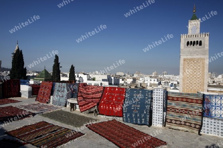 Eine Dachterrasse mit Teppichen und die Moschee Zaytouna oder Grosse Moschee im Souq oder Bazzar in der Altstadt  von Tunis am Mittelmeer in Tunesien in Nordafrika..