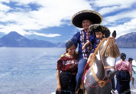 People at the coast of Lake Atitlan mit the Volcanos of Toliman and San Pedro in the back at the Town of Panajachel in Guatemala in central America.   