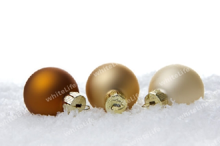 creme und beige Christbaumkugeln auf Kunstschnee mit weissem Hintergrund