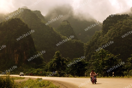 Die Landstrasse 12 beim Dorf Mahaxai Mai von Tham Pa Fa unweit der Stadt Tha Khaek in zentral Laos an der Grenze zu Thailand in Suedostasien.