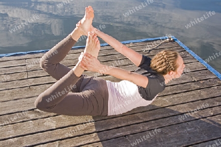 Junge Frau beim Yoga am See
Young woman doing yoga by the lake