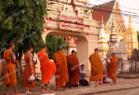 Moenche auf ihrem Rundgang am fruehem Morgen vor dem Tempel Wat Sainyaphum in der Stadt Savannahet in zentral Laos an der Grenze zu Thailand in Suedostasien.