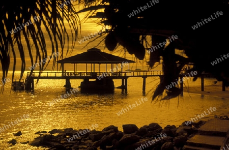 Ein Hotelstrand mit Pavillon bei Sonnenuntergang auf der Insel Praslin auf den Seychellen im Indischen Ozean.