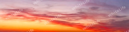 Beautiful high resolution panorama of orange and red sunset clouds in the evening sky.