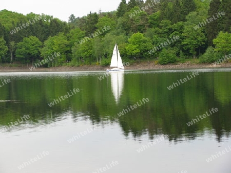 Segelschiff mit Spiegelung im See