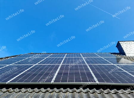 Solar panels producing clean energy on a roof of a residential house with black roof tiles