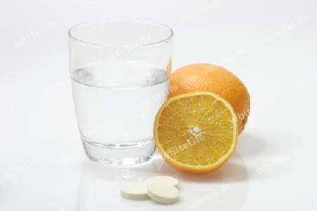 Orange mit einem Glas Wasser und Brausetabletten auf hellem Hintergrund