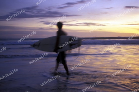 Ein Surfer am Strand der Kuta Beach im sueden der Insel Bali, Indonesien.
