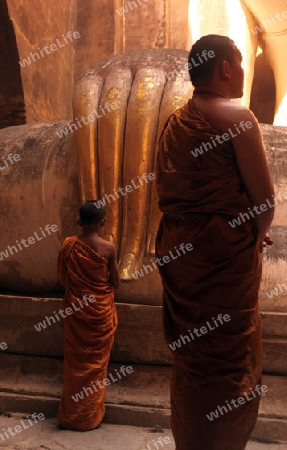 Moenche bestaunen die Buddha Figur  im Wat Si Chum Tempel in der Tempelanlage von Alt-Sukhothai in der Provinz Sukhothai im Norden von Thailand in Suedostasien.