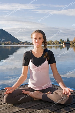 Junge Frau beim Yoga am See
Young woman doing yoga by the lake