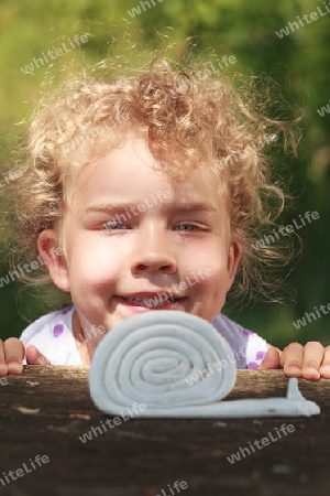 L?chelndes kleines M?dchen mit sch?nen lockigen blonden Haaren