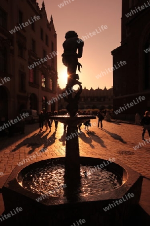 Ein Brunnen im Abendlicht beim Rynek Glowny Platz in der Altstadt von Krakau im sueden von Polen.