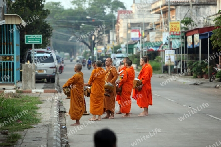 Moenche auf ihrem Rundgang am fruehem Morgen vor dem Tempel in der Stadt Tha Khaek in zentral Laos an der Grenze zu Thailand in Suedostasien.