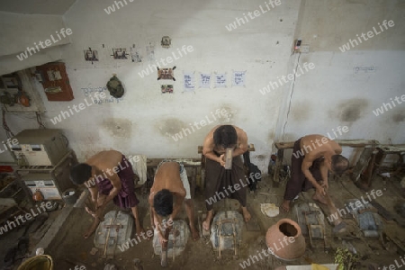 workers pound sheets of Gold leaf at a Gold pounder Factory the City of Mandalay in Myanmar in Southeastasia.