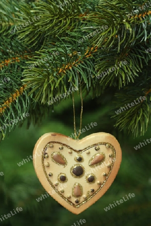 Dekorativer Weihnachtsschmuck an einem Tannenzweig auf gruenem Hintergrund