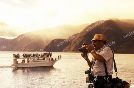 People at the coast of Lake Atitlan mit the Volcanos of Toliman and San Pedro in the back at the Town of Panajachel in Guatemala in central America.   