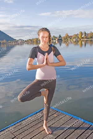 Junge Frau beim Yoga am See
Young woman doing yoga by the lake