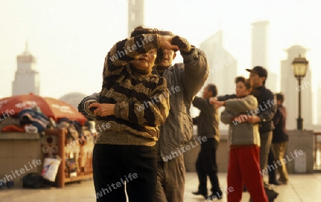 people dancing in the morning on the Bund in front of the skyline of Pudong in the City Shanghai in China.