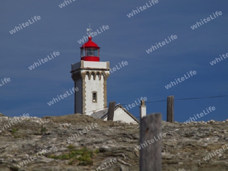 Leuchtturm mit roter Spitze vor blauem Himmel